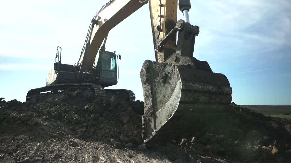 Excavator bucket cutting into the ground on a DuPage County septic job